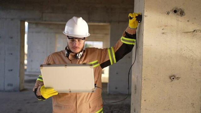 a worker engineer in a white helmet and uniform inspects the quality scanning of concrete by ultrasonic machines
