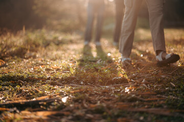 Woman walking in meadow at sunrise, closeup to a leg of female family in the morning at natural park or forest trail, feeling of relaxation and happy time, Young woman hiking and going sport camping