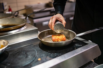 man chef cooking fried tuna fish in frying pan on kitchen
