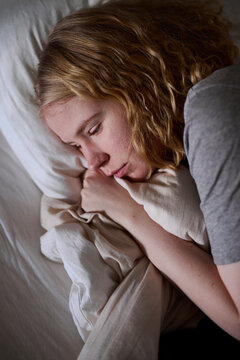 Crying young woman lying in bed
