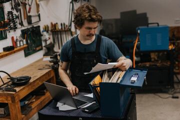 Blacksmith looking at document in workshop