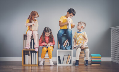 Group of children sitting on the book's stacks and on the bookshelves in the room and reading...