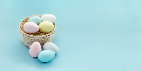 Easter eggs in a wicker basket on blue background.