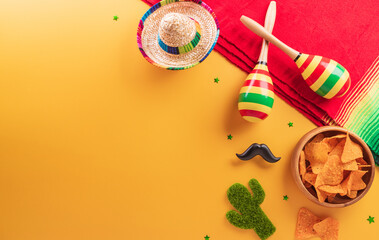 Cinco de Mayo holiday background made from maracas, mexican blanket stripes or poncho serape, cactus and hat on yellow background.