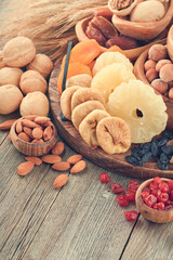 Tu Bishvat celebration concept. Mix of dry fruits and nuts almonds, hazelnuts, walnuts, apricots, prunes, cherries, raisins, dates, apples, figs over wooden table. Jewish holiday, new year of trees.