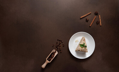 Top view of Layered Cake with cream Napoleon with mint on Brown background. A cinnamon stick, badyan, coffee beans on a brown background. Copy space