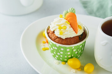 Carrot cake cupcakes for Easter. Carrot cupcakes with cream cheese frosting decorated with tiny marzipan carrots on white background. Happy Easter and spring holiday concept. Holydays homemade