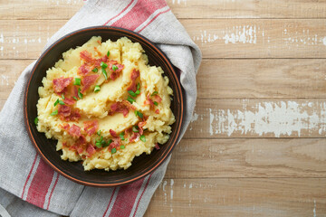 Mashed potatoes. Bacon mashed potatoes with green onion, pepper and cheddar cheese in bowl on old wooden backgrounds. Delicious creamy mashed potatoes. Top view.