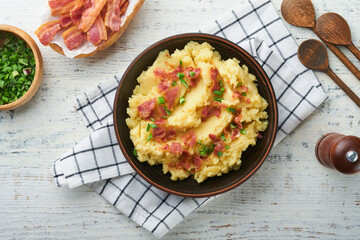 Mashed potatoes. Bacon mashed potatoes with green onion, pepper and cheddar cheese in bowl on old wooden backgrounds. Delicious creamy mashed potatoes. Top view.