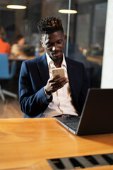 Portrait of successful businessman in office. Young smiling man using the phone..