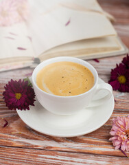 A cup of fragrant fresh cappuccino and flowers on the table in the morning. Spring composition. Selective focus.