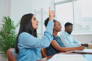 Young business woman raises hand in boardroom meeting to ask question
