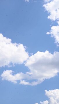 Vertical video of white clouds against a blue sky on a sunny day