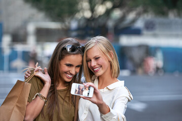 Taking a shopping spree selfie. two young women taking a selfie while out shopping in the city.