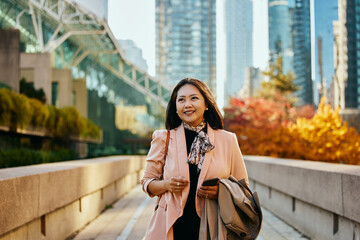 Happy Asian businesswoman after work on city street. © Drazen