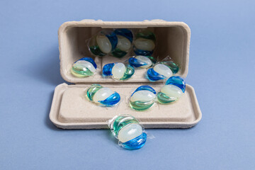 Gel for washing in capsules. Laundry detergent in biodegradable packaging on blue background