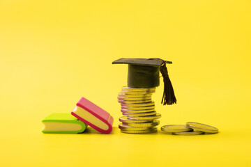 Graduated cap with coins on yellow background. Savings for education or financial literacy concept - obrazy, fototapety, plakaty