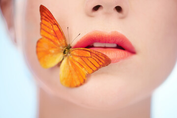 Spring-fresh skin. A butterfly sitting on the side of a womans mouth.