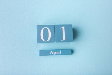 Wooden calendar with the date of April 1, on a blue background. April Fools' Day