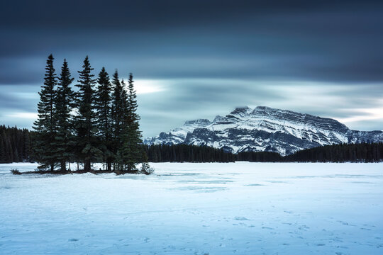 Two Jack Lake with Mount Rundle and pine forest in winter on the evening at Banff national park