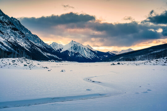 Sunrise over Medicine Lake with rocky mountains and frozen lake in Jasper national park