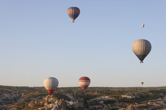 Panoramic image of hot air balloons flying in clear blue sky.