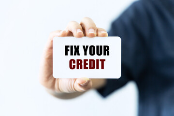 Fix your credit text on blank business card being held by a woman's hand with blurred background. Business concept about fixing your credit.