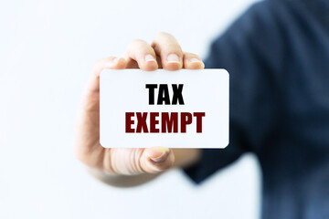 Tax exempt text on blank business card being held by a woman's hand with blurred background. Business concept about tax exempt.