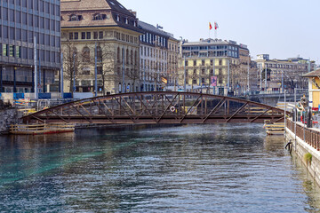 Scenic view of Rhone River with iron pedestrian bridge named passerelle de l’Île at Swiss City of Geneva on a sunny winter day. Photo taken March 5th, 2023, Geneva, Switzerland.