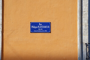 Blue street name sign of patron Philippe Pantamour against yellow facade at Swiss City of Geneva on...