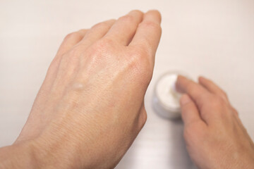 A woman takes out a hand cream from a jar. The concept of care, cosmetic procedures.
