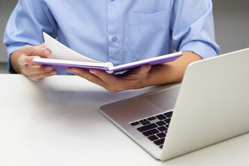 Close up hand of businessperson are opening a read book and laptop in front. Concept of business...