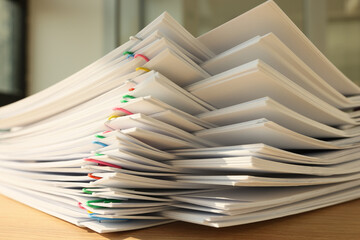 High stack of office documents with clips on office table close up.