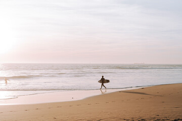 Silueta de surfista entrando en el agua al atardecer en playas de andalucia