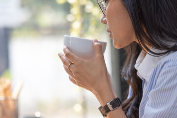 Beautiful young Asian woman working on laptop computer while sitting at the plan office space after working hours, Asian woman drinking coffee