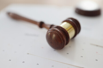 Wooden judge gavel on calendar pages, shallow depth of field.