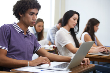 Focused on their assignments. a group of university students working on laptops in class.