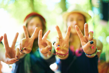 Peace, love and happiness. Three young woman wearing colourful nail polish showing a peace sign to the camera.