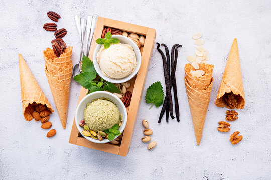 Pistachio and vanila ice cream in bowl with mixed nuts setup on white stone background . Summer and Sweet menu concept.