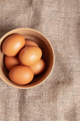 Chicken eggs in bowl on burlap background. Fresh natural eggs. Vertical. Soft focus
