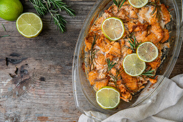 Salmon bites baked in oven with lime and rosemary and on rustic wooden table.