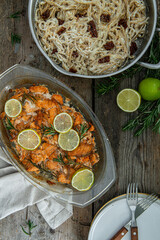 Salmon bites baked in oven with lime and rosemary and cream sauce on rustic wooden table.