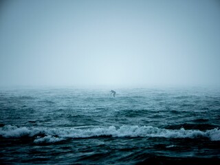 Man paddling on a rough sea during foggy day