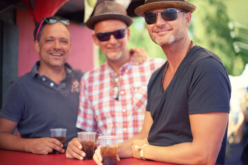 Sharing a drink amongst friends. three male friends drinking at a festival.