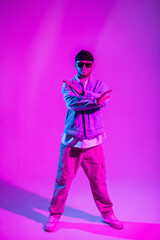 Handsome professional dancer man in trendy fashion denim clothes dancing in a creative studio with pink and neon light