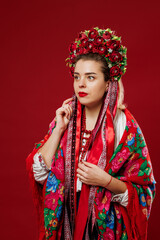 Portrait of ukrainian woman in traditional ethnic clothing and floral red wreath on viva magenta studio background. Ukrainian national embroidered dress call vyshyvanka. Pray for Ukraine