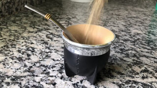 Preparing a mate by putting yerba in the mate. Argentine custom to drink mate at all times