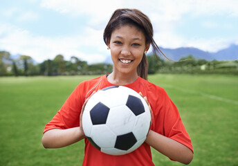 In it to win. a young female soccer player holding a soccer ball.