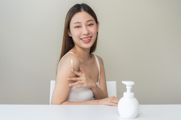 Obraz na płótnie Canvas Healthy skin care, beauty asian young woman in casual, towel after shower bath at home, hand in applying, putting moisturizer on her arm. Skin body cream moisturizing lotion, routine in the morning