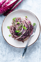 Risotto with radicchio and red wine decorated with fresh herbs, winter Nord Italy dish. Radicchio...